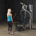 Female athlete performing tricep pushdown on Body-Solid G5S Home Gym, standing further from the machine.