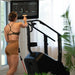 Female athlete next to the STEPR+ Stair Climber using the swivel display to prepare for off-machine exercises, demonstrating versatility and workout options.