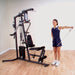 Woman performing a one-arm lateral side raise with a low row cable attachment in a standing position on the Body-Solid G3S