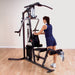 Woman performing a single leg kickback using the low pulley attachment on the Body Solid Home Gym G3S